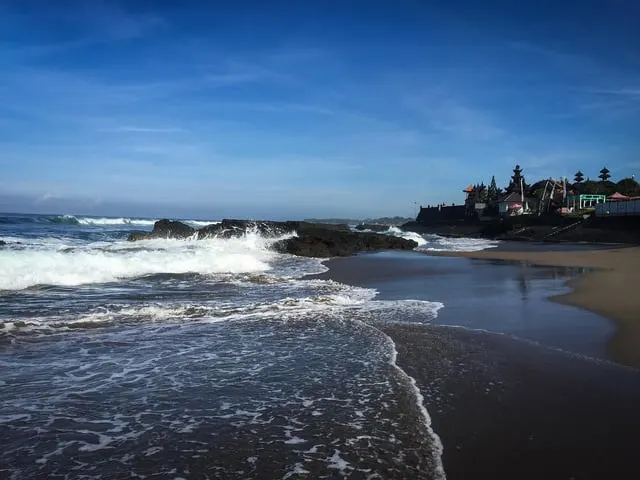 evaychen / Pixabay / Pixabay Content License Waves on the black-sand shore at Batu Bolong, Canggu, with the temple on the rocks