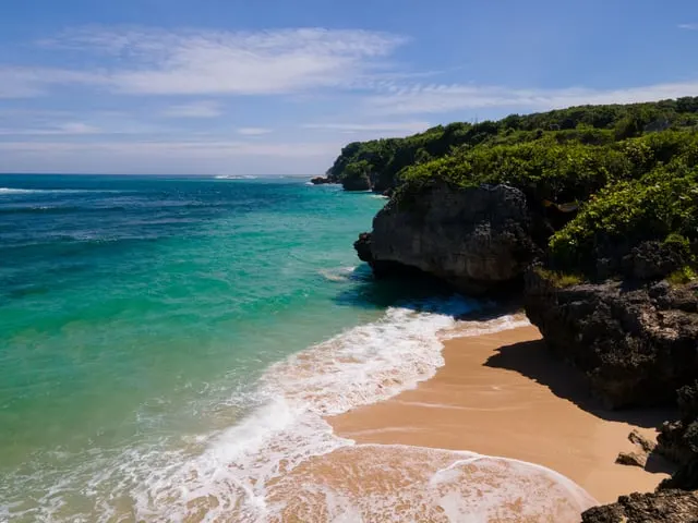 A small sandy cove below green cliffs on the Bukit
