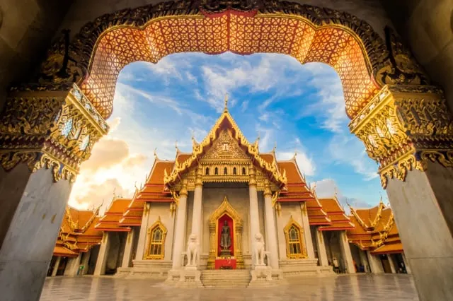 Wat Benchamabophit, the Marble Temple in Bangkok, seen through a gilded arch at golden hour