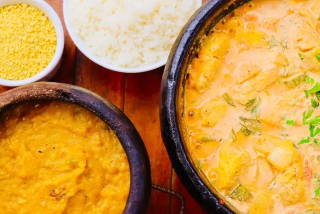 Fish moqueca in a clay pot with sides