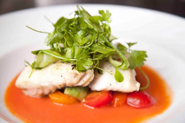 White fish with greens on a red pepper sauce
