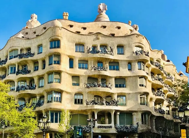 Troovz La Pedrera's rippling stone façade and rooftop chimneys under a blue sky