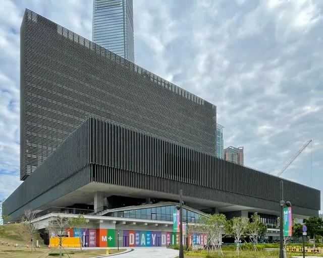 The M+ museum's long slab building, cloudy sky
