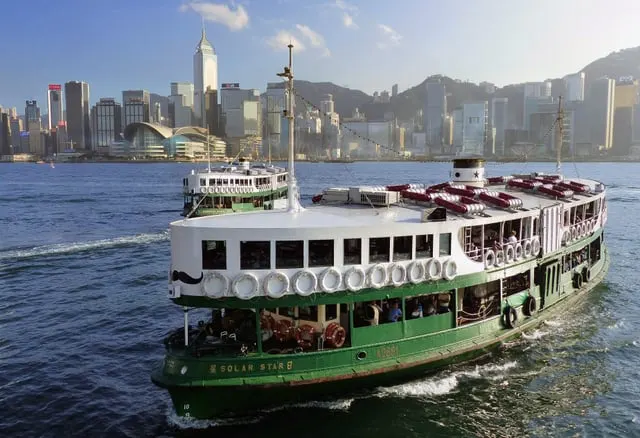 A green-and-white Star Ferry crossing the harbour, blue sky