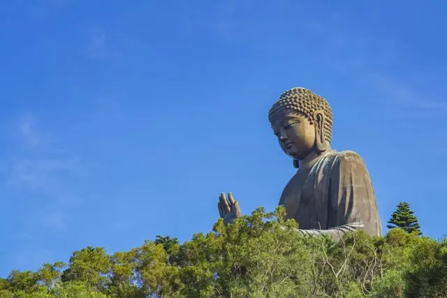The Tian Tan Buddha above green trees, blue sky
