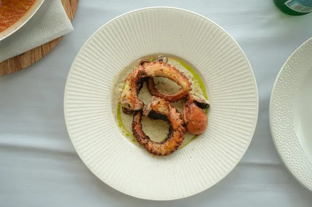 Grilled octopus with olive oil in a white bowl