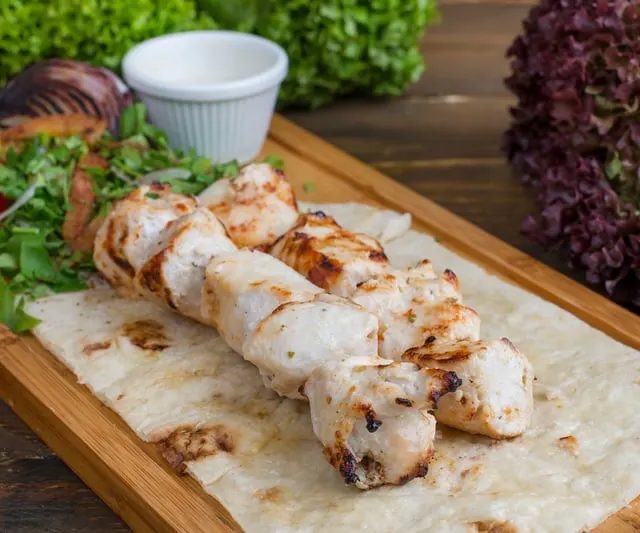 Grilled chicken skewers on flatbread with salad