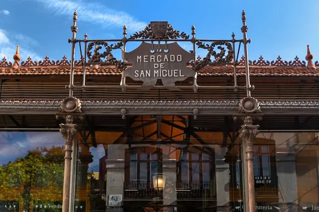 Jorge Franganillo / Flickr / CC BY 2.0 The Mercado de San Miguel's iron entrance and sign, blue sky