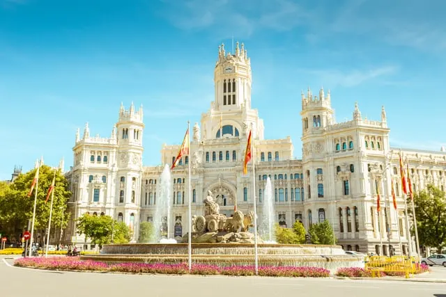 The Cibeles fountain and palace with flower beds, blue sky