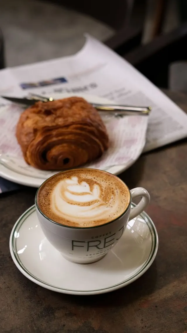 Typical cappuccino with latte art and a croissant