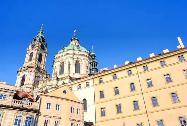 St Nicholas Church's green dome and bell tower over Malostranské Square, blue sky
