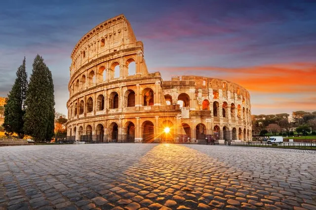 The Colosseum in Rome at sunrise, with the sun shining through an arch