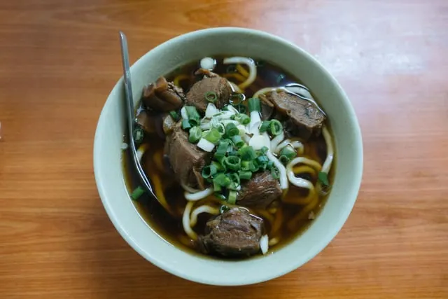 Beef noodles with spring onion in a green bowl