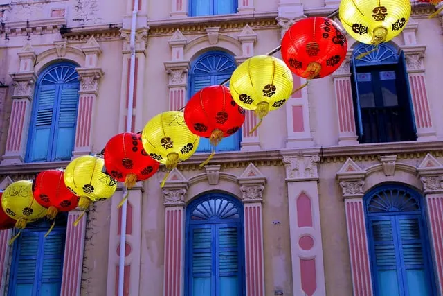 Red and yellow lanterns along a pink Chinatown shophouse