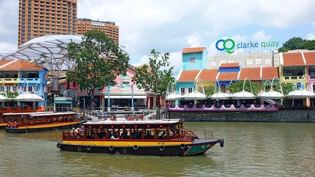 Clarke Quay's coloured shophouses and a river bumboat, sunny